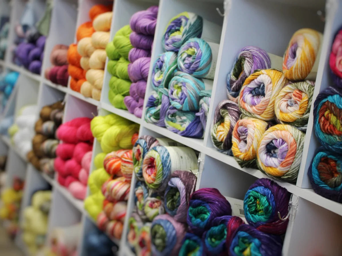 Skeins and cakes of yarn arranged on shelves at Luv2Knit & More